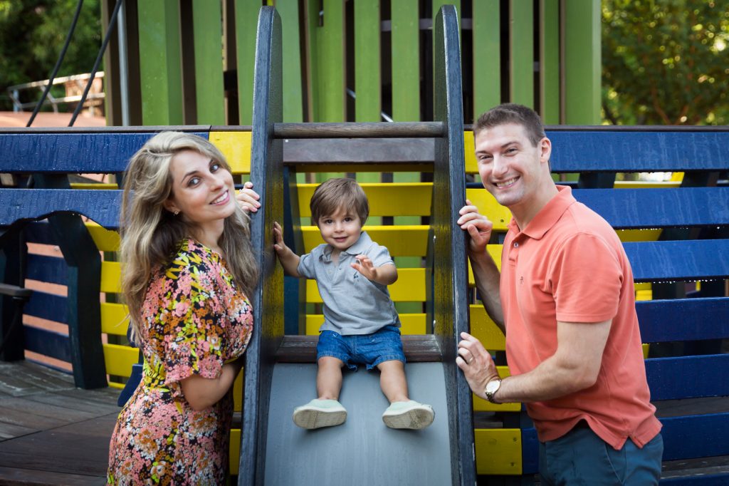 Parents with little boy on slide during a Chelsea Waterside Park family portrait session