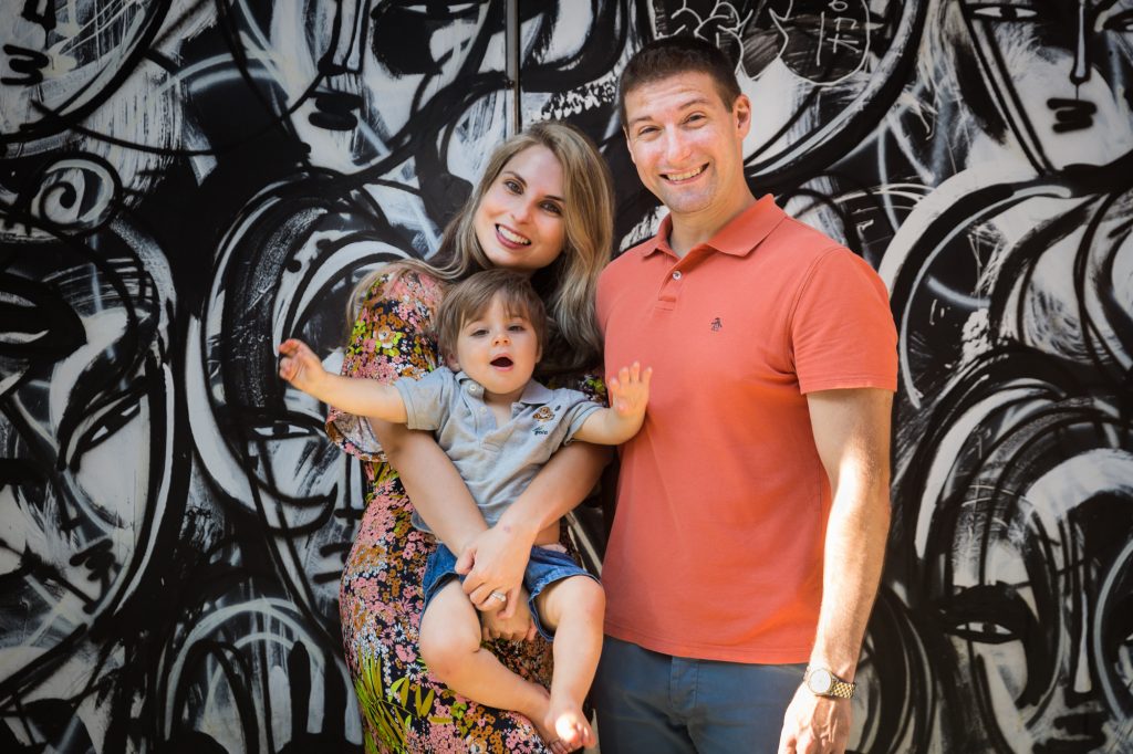Parents with little boy in front of black and white graffiti wall