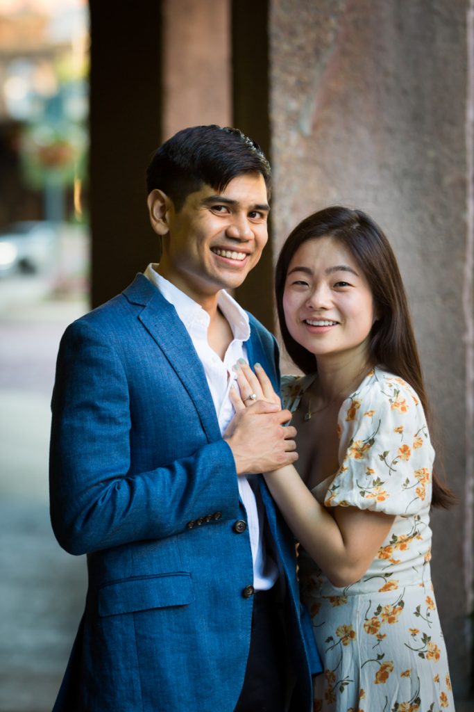 Couple holding hands by column during Queens engagement photo session