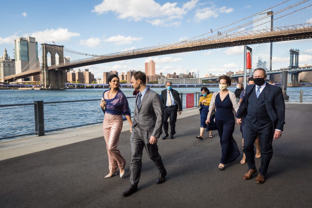 Bride and groom leading family through Brooklyn Bridge Park