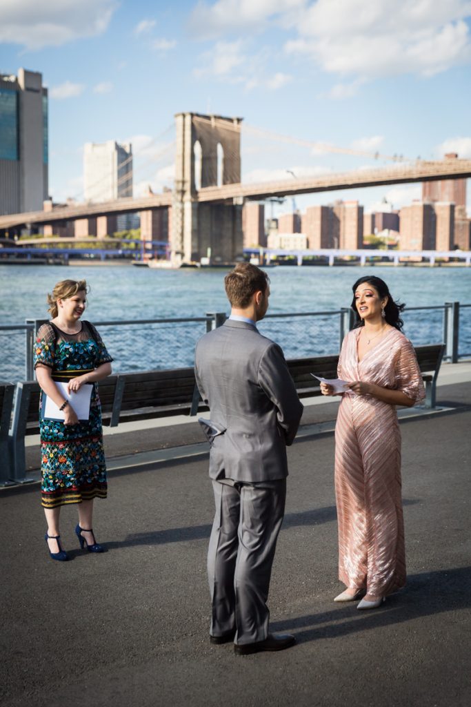 Bride and groom saying vows in front of Brooklyn Bridge