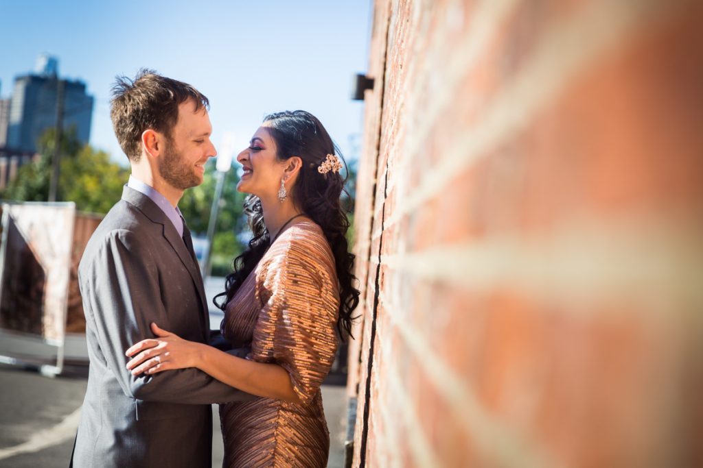 Bride and groom leaning against brick wall