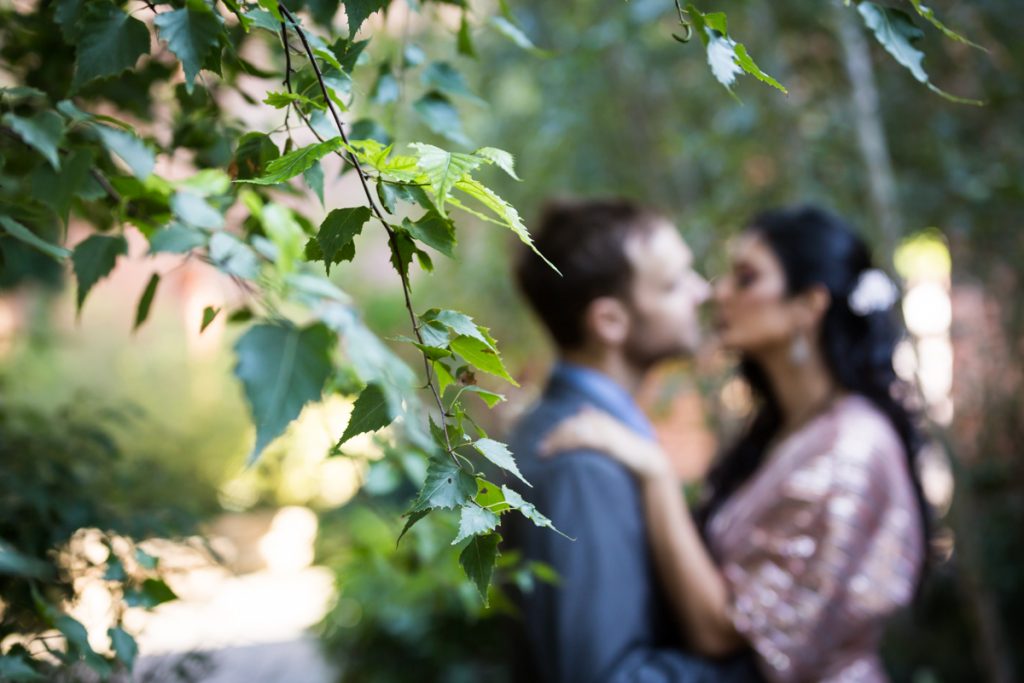 Bride and groom kissing behind branch in Max Family Garden