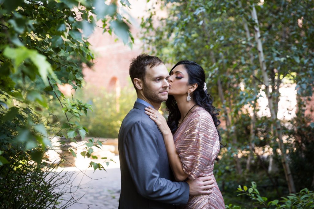Bride kissing groom's cheek in Max Family Garden