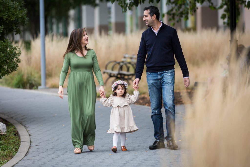 Parents holding hands of little girl during a Riverside Park family portrait session