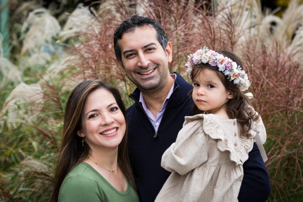 Parents and little girl in front of pink bushes during a Riverside Park family portrait session