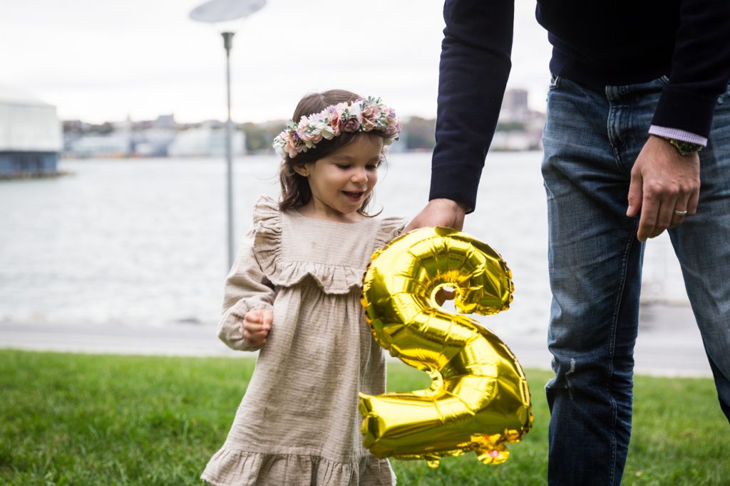 Father handing number 2 balloon to little girl