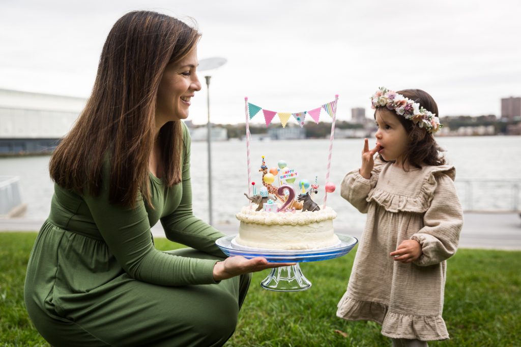 Mother showing cake to little girl during a Riverside Park family portrait session
