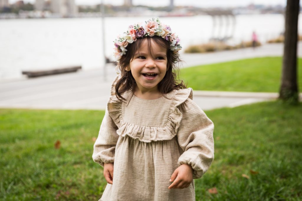 Little girl laughing and wearing flower crown in Riverside Park