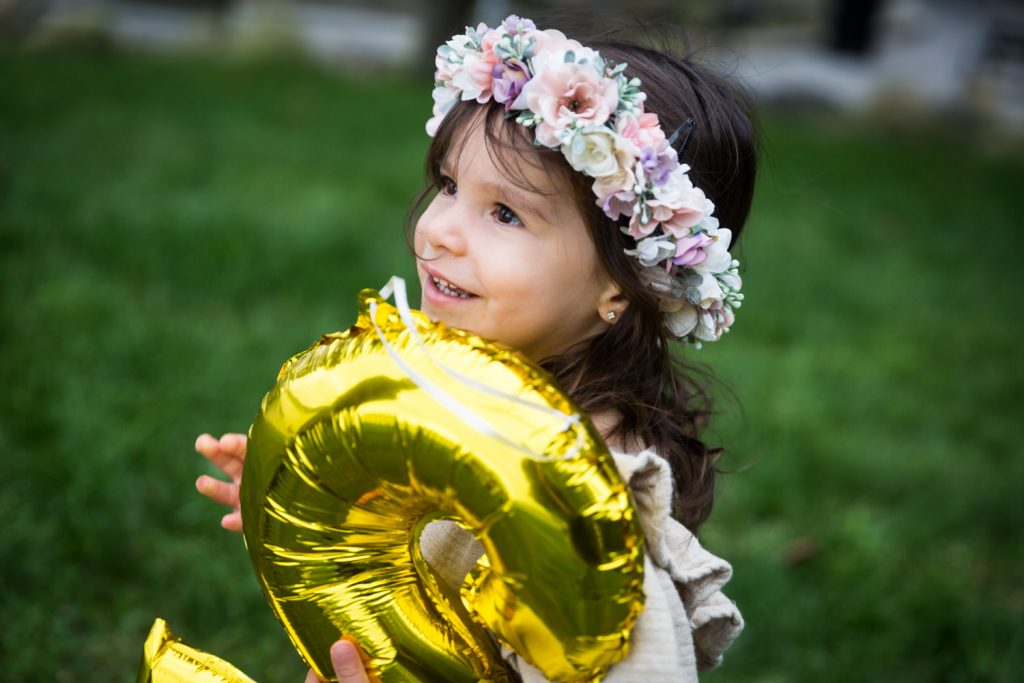 Little girl wearing flower crown and holding gold balloon