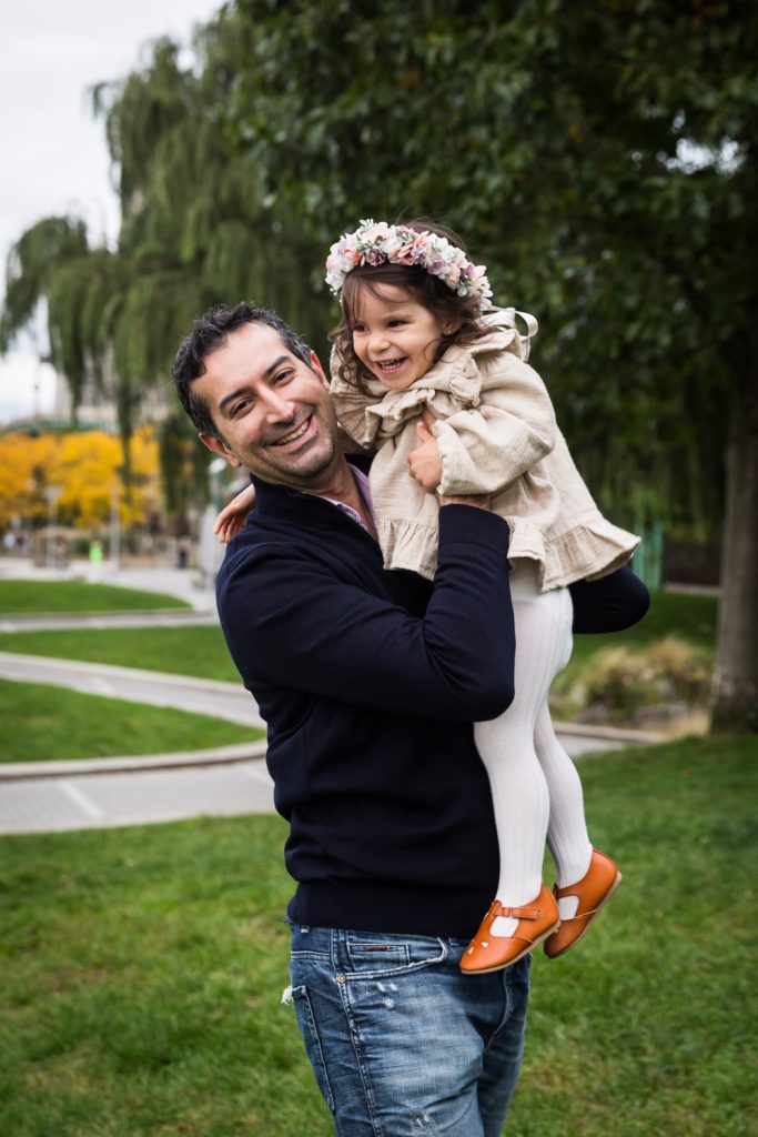 Father holding little girl wearing flower crown in Riverside Park