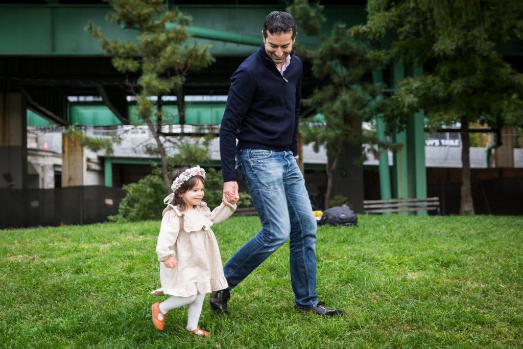 Father holding little girl's hand during Riverside Park family portrait