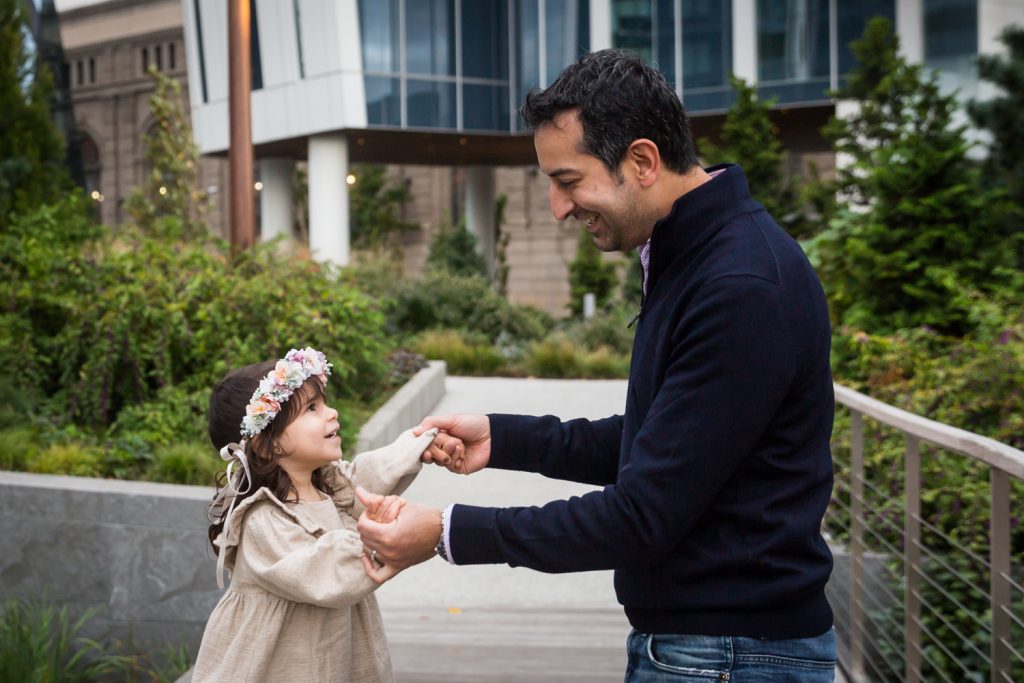 Father holding hands of little girl and dancing in Waterline Square Park
