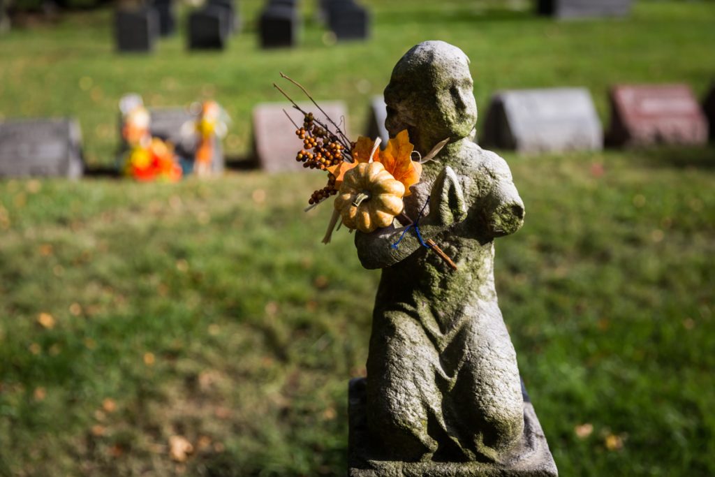 Grave statue holding fall pumpkin decoration