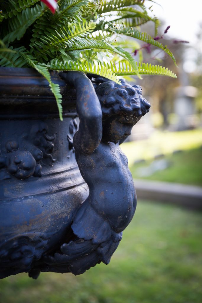 Cherub holding up plant urn at Green-Wood Cemetery