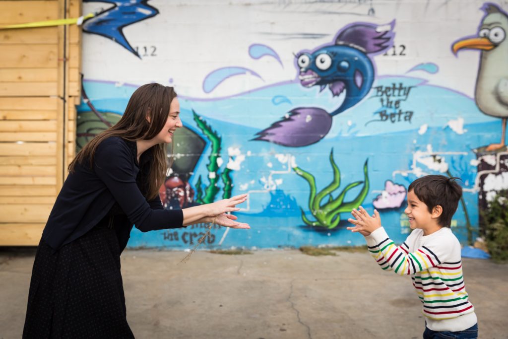 Mother and son playing shark in front of colorful mural