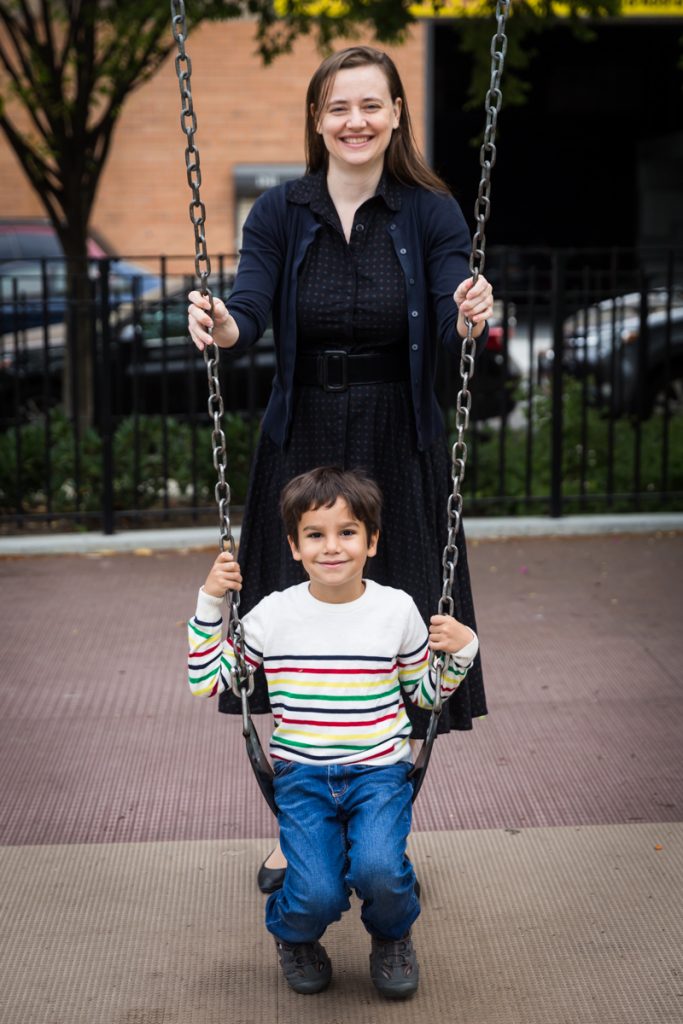 Mother standing over boy on swings during a Gowanus family portrait session