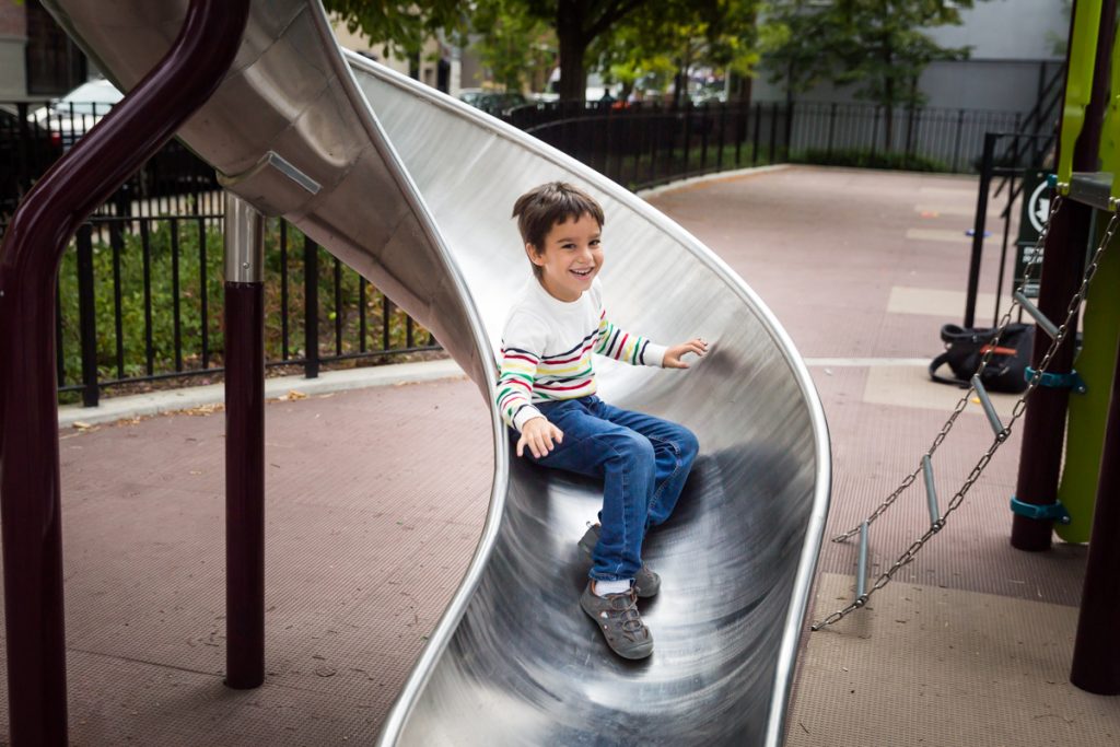 Little boy sliding down slide in Ennis Playground