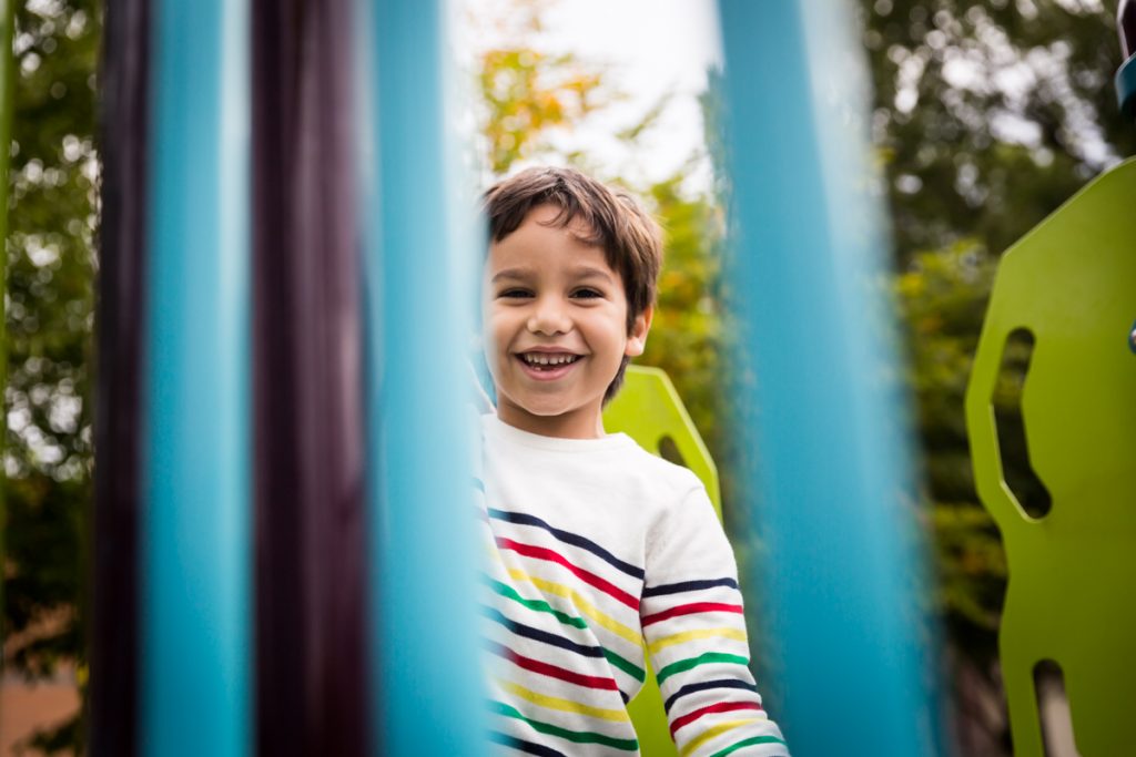 Boy looking through jungle gym bars at an Ennis Playground family portrait session