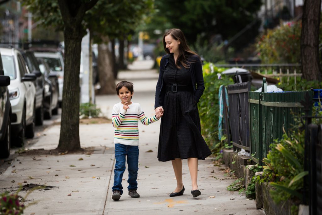 Mother and son walking down Brooklyn sidewalk holding hands
