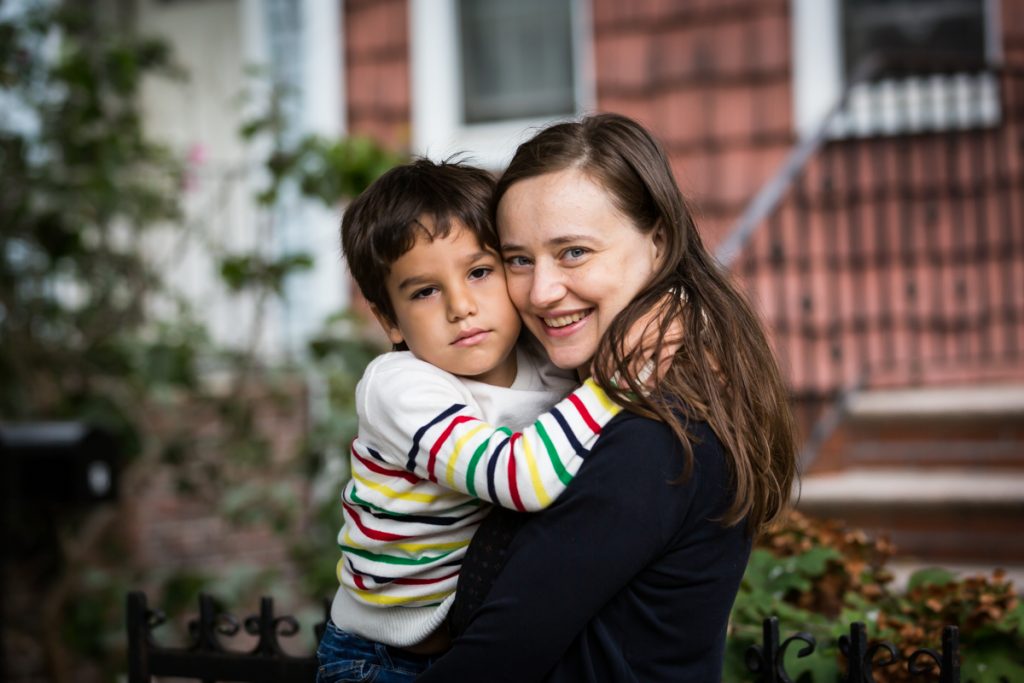 Mom and son hugging in front of house during a Gowanus family portrait session