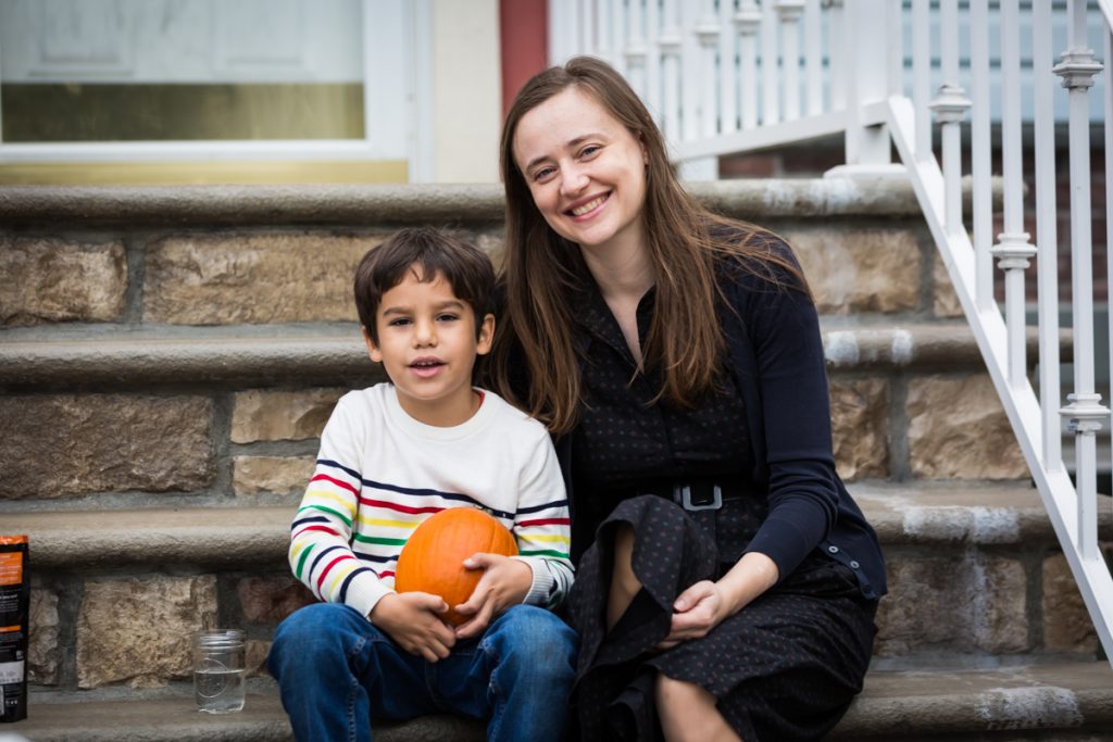 Mother and son sitting on steps with small pumpkin