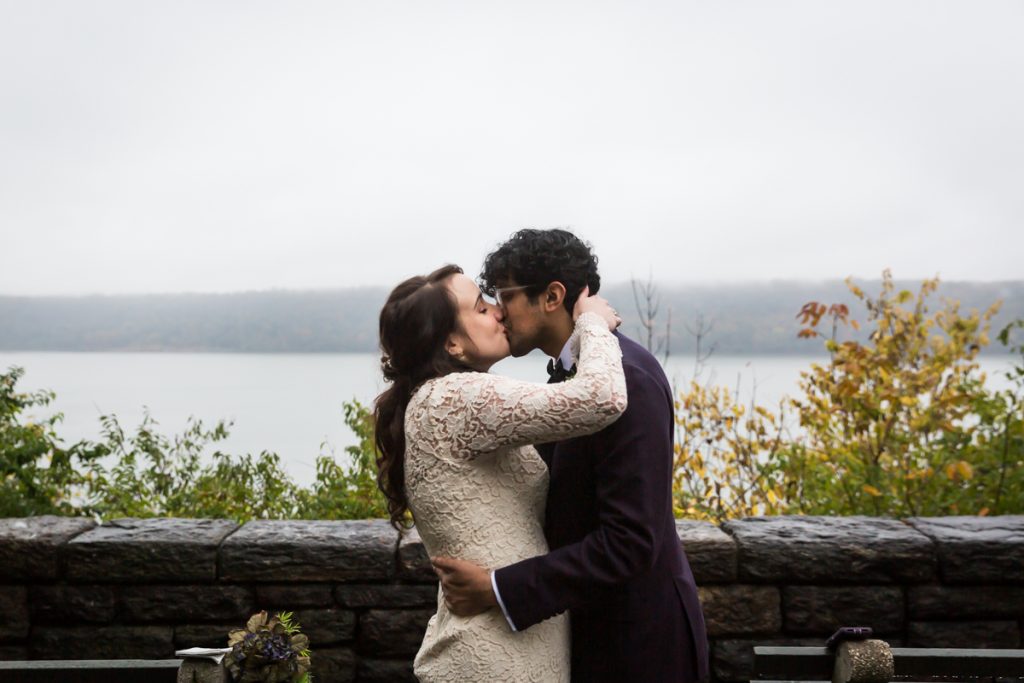 Couple kissing with Hudson River view for an article on how to get married in Fort Tryon Park