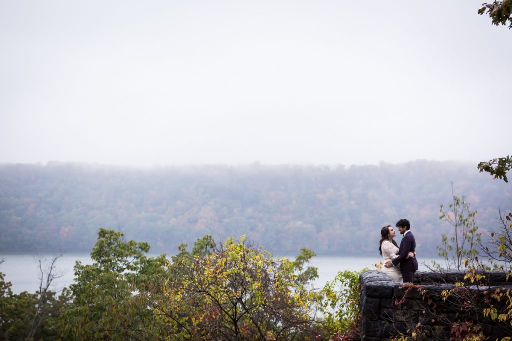 Couple kissing against stone wall for an article on how to get married in Fort Tryon Park