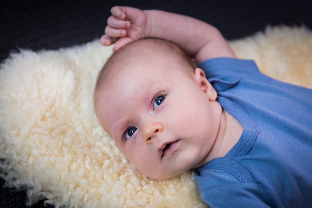 Newborn baby in blue onesie for an article on how to prepare for a newborn portrait session