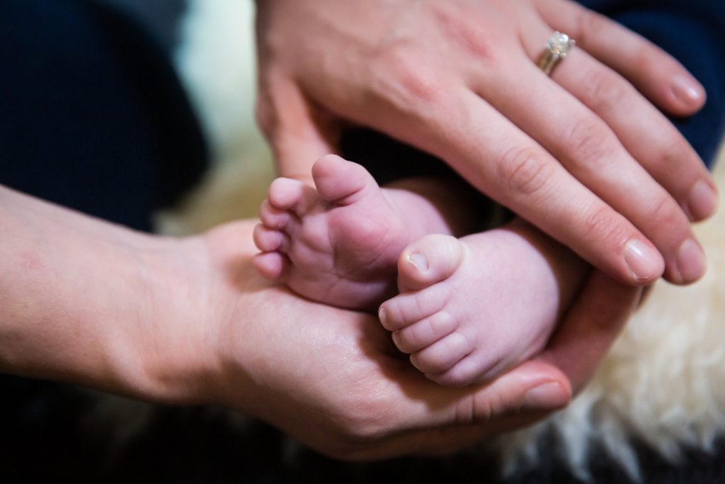 Close up on hands holding newborn baby's toes
