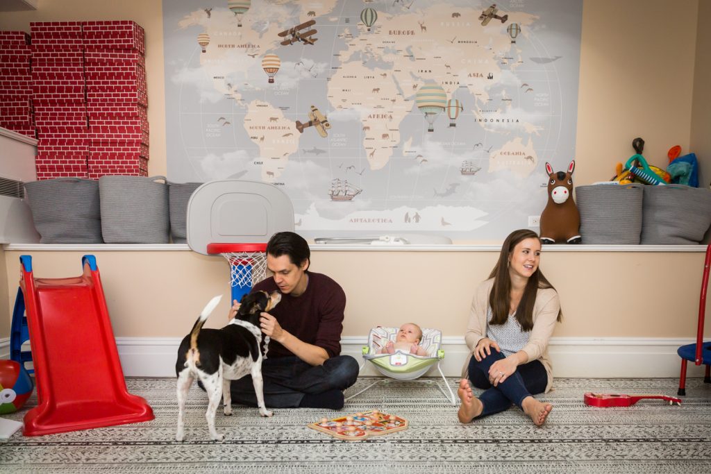 Parents playing with dog and kids on carpet