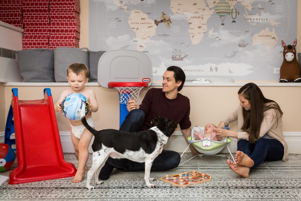 Parents playing with two young children for an article on how to prepare for a newborn portrait session