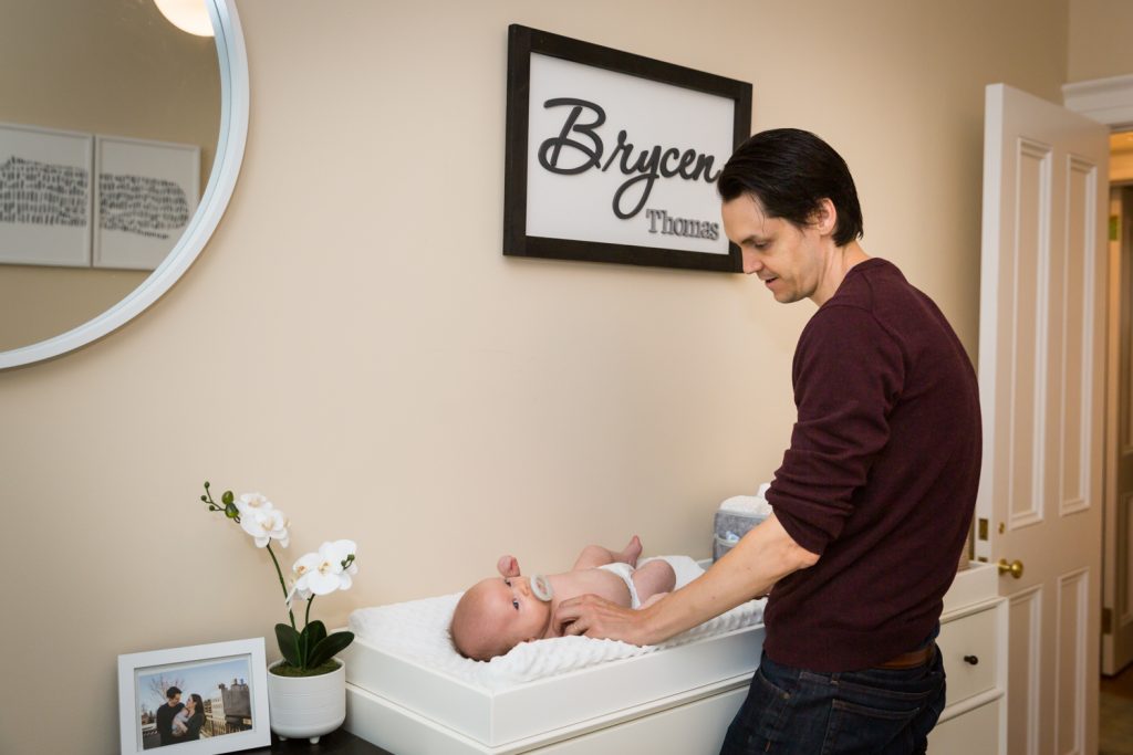 Father changing newborn baby's diaper for an article on how to prepare for a newborn portrait session