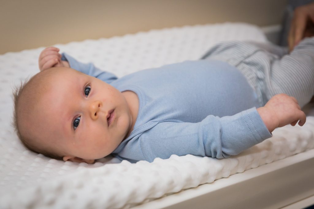 Newborn baby boy wearing blue shirt on diaper changing table