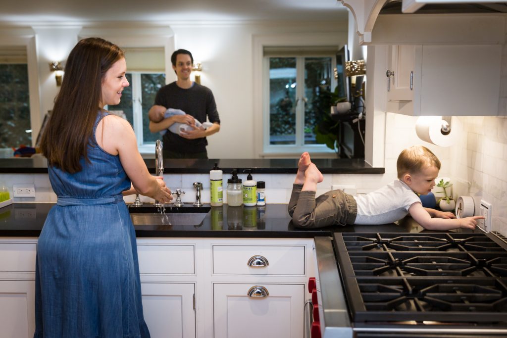 Parents watching toddler on kitchen counter 