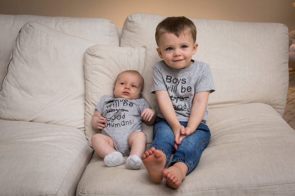 Newborn boy and baby brother on couch for an article on how to prepare for a newborn portrait session