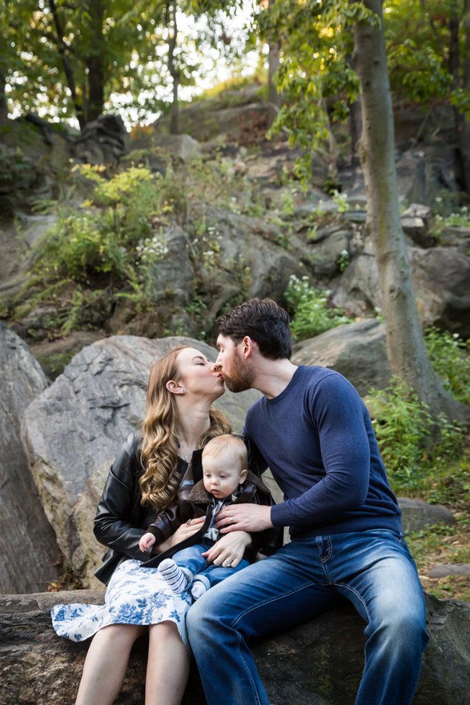 Parents kissing and holding baby boy during a Marcus Garvey Park family portrait session