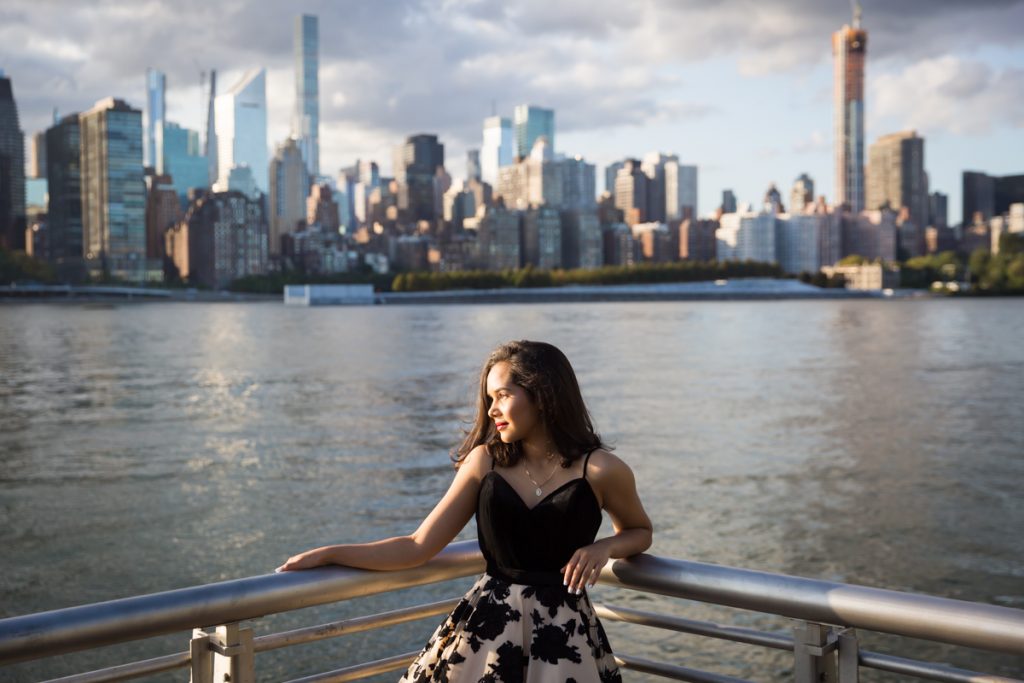 Girl in corner of railing with NYC skyline background