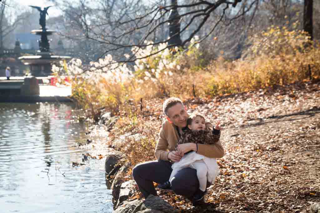 Father with little girl sitting beside Central Park Lake