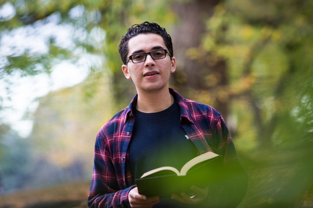 Young man holding book during a Central Park senior portrait session