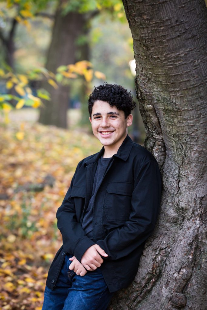 Young man leaning against tree during a Central Park senior portrait session