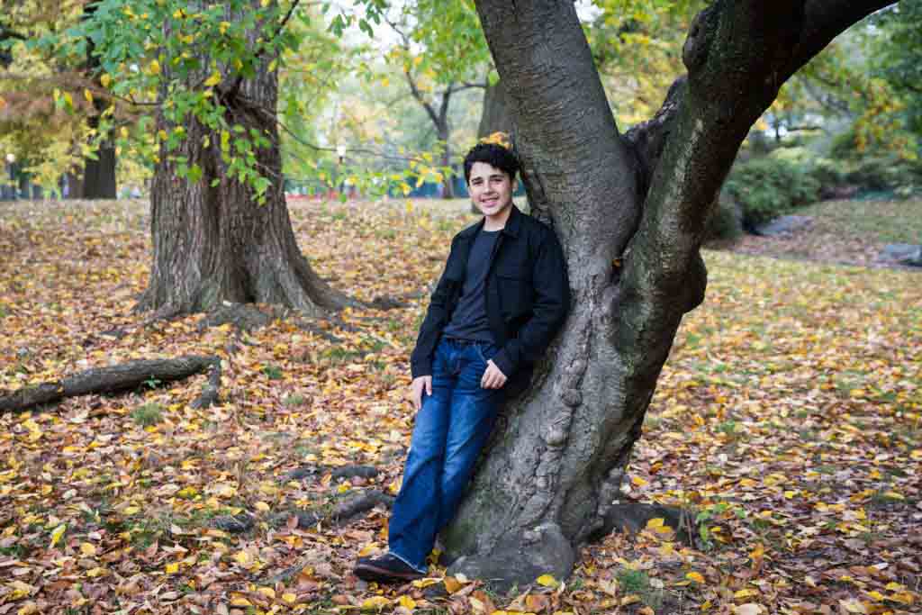 Young man leaning against tree in Central Park