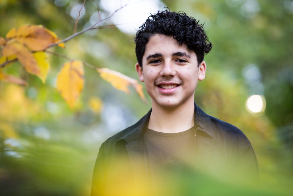 Young man seen through branches during a Central Park senior portrait session
