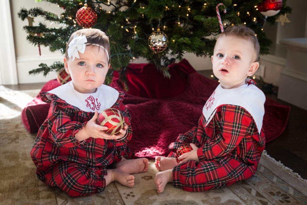 Two babies in matching plaid pajamas for an article on holiday family portrait ideas