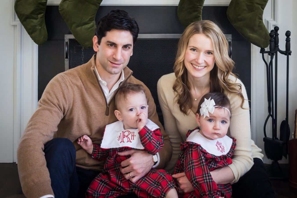 Parents holding baby twins in front of a fireplace for an article on holiday family portrait ideas