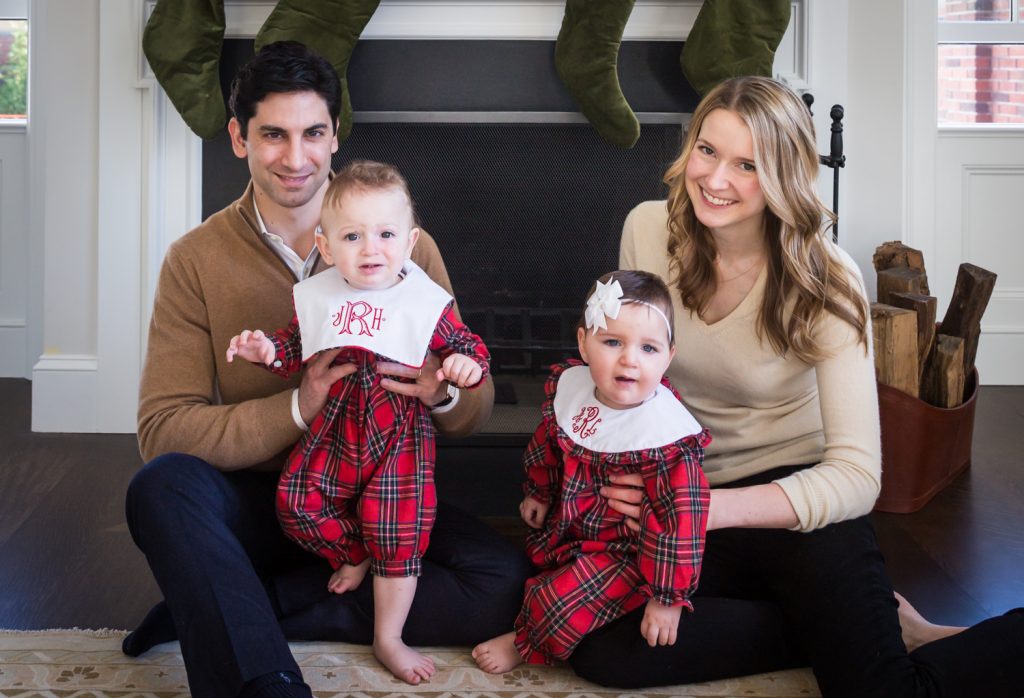 Parents holding baby twins in front of a fireplace for an article on holiday family portrait ideas
