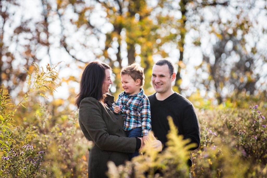 Parents holding little boy in front of plants for an article about a Forest Park photo shoot neighborhood discount offer