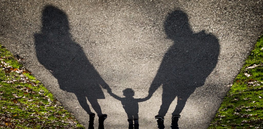 Shadow on ground of parents holding child by the hands