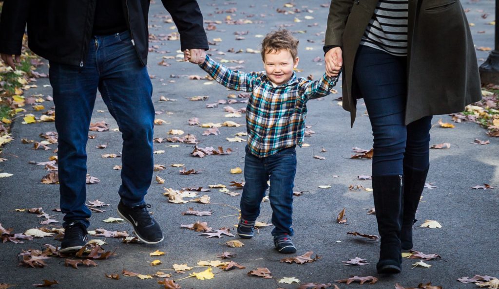 Little boy walking with parents hand-in-hand