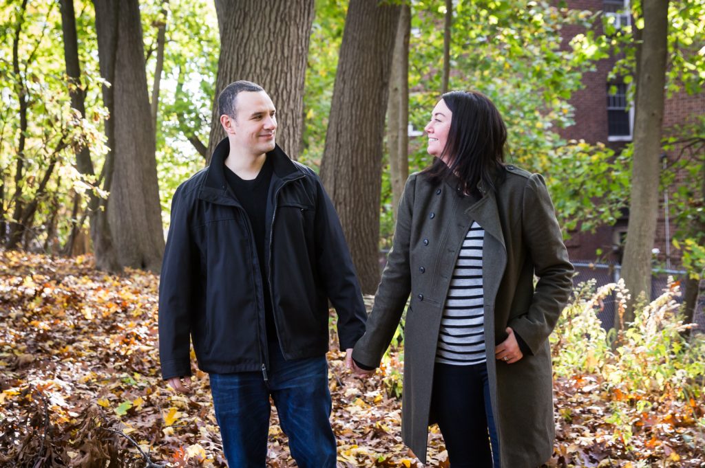 Couple holding hands and walking in woods Parents holding little boy in front of plants for an article about a Forest Park photo shoot neighborhood discount offer